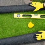 Above shot of artificial grass roll and tools in contractor hands