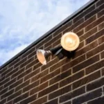 A spotlight mounted on an exterior brick wall.